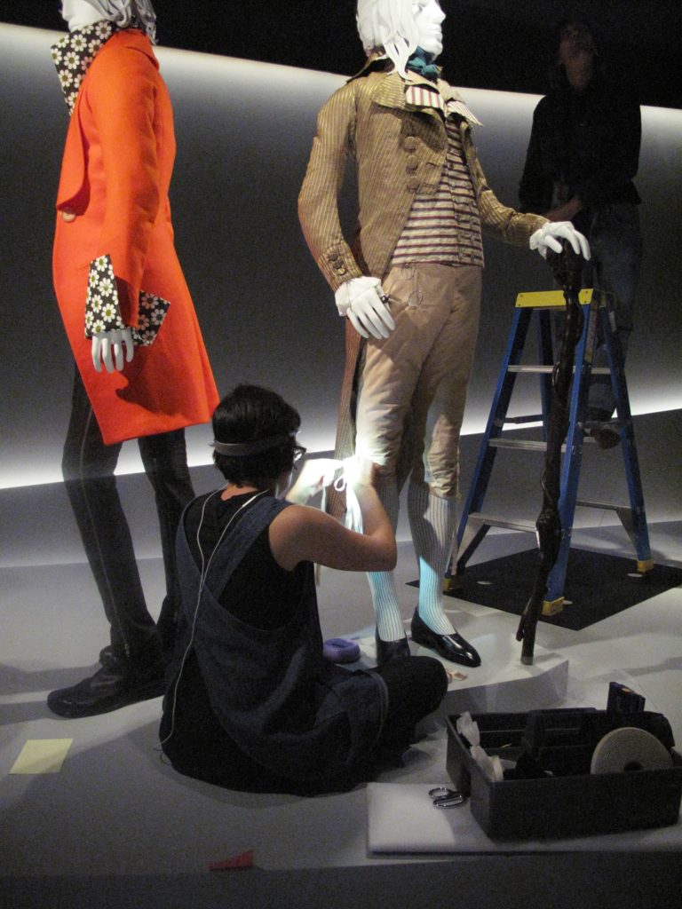Rachel Tu, Collections Manager (LACMA) tying the reproduction silk bows on the breeches of the Incroyable ensemble, 1790